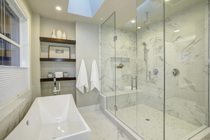 Salle de bains moderne avec armoire en chêne blanc avec plan de travail en marbre blanc, miroir circulaire doré, douche avec hexagone en marbre et carrelage rectangle